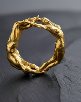 Gold vermeil lovers ring featuring male and female figures forming a circle on dark textured background