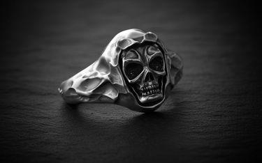 Close-up front view of silver hooded skull ring featuring oxidized eye sockets and textured hood on black slate