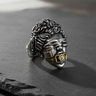 Silver Justice Ring with a brass dollar sign gag, shown at an angle on a dark slate surface to highlight the detail.