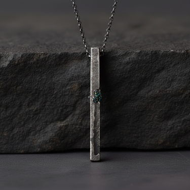 Front view of vertical silver bar necklace hanging against textured slate background