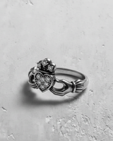 Side profile of black Irish Claddagh ring featuring intricate design and paved clear stones