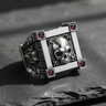 Front view of 925 sterling silver vampire skull ring with red gemstones on black slate background