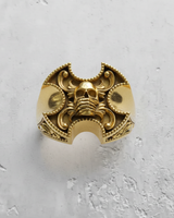 Front view of gold vermeil gothic skull ring with ornate filigree details on textured background