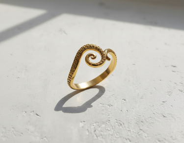 Gold vermeil over 925 sterling silver octopus tentacle ring with spiral design on textured white background