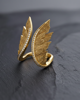 Gold vermeil angel wings ring with pave stones on the edge displayed on black texture