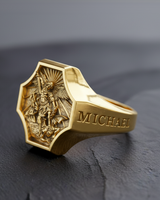 Gold plated version of Archangel Michael signet ring displaying high relief sword and demon imagery on dark stone background