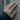 Hope Shield Band Ring worn on model hand against concrete wall