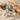Close-up of elegant sterling silver floral ring with green marquise stones displayed on sand next to natural driftwood