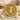 Close-up of 14K gold vermeil Medusa coin ring resting beautifully on textured white sand and pebbles in natural light