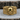 Close-up of premium Greek key skull ring resting on rustic wooden surface, displaying detailed gothic craftsmanship