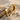 Beautiful three stone engagement ring displayed on textured sand and rustic driftwood showcasing brilliant gemstones
