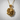 Close-up angled view of the handcrafted gold rose pendant resting against a textured white wall background