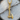 Close-up of the gold battle axe pendant resting on a wooden log, highlighting the detailed runic engravings and texture