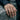 Lifestyle shot of a double Venus pride ring worn on a woman's hand resting on a textured gray stone background