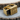 Handcrafted secret compartment ring resting on wood, displaying the intricate filigree and slide mechanism craftsmanship.