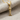 Close-up of polished gold fish bone pendant resting on textured fabric highlighting intricate spine detail