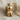 Close-up of gold teddy bear pendant showcasing intricate 3D design and polished finish on textured fabric