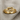 Close-up of polished 14K gold vermeil infinity knot ring resting perfectly on a textured natural linen fabric surface