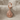 Conch spiral shell earring, rose gold, front view on neutral fabric