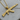 Close-up of the finely crafted 14K gold vermeil ornate rifle pendant resting on a textured wooden cross-section surface