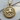 Close-up of gold vermeil Saint George round relief pendant resting on natural wood showing detailed craftsmanship