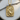 14K gold vermeil koi fish pendant resting flat on a circular wooden slice next to a small rustic tree branch