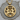 Close-up of the intricately carved Gemini pendant resting flat on a natural wooden tree bark surface for display