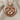 Heart frame baby feet pendant, rose plated silver, front view on textured fabric