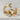 Close-up view of polished gold finish deer antler statement ring displayed on textured white stone surface