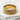 Gold Japanese crane ring displayed on a textured white stone surface showcasing intricate artisan craftsmanship