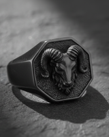 Front view of handcrafted silver ram head ring with octagonal signet design on dark textured background