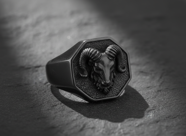 Front view of handcrafted silver ram head ring with octagonal signet design on dark textured background
