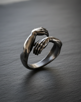 Side view of oxidized silver hug ring showing detailed fingers and muscle texture with vintage finish
