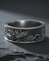 Detailed close-up of handcrafted silver ring showing crane, waves, and floral motifs in oxidized finish