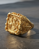 Gold vermeil St George ring featuring detailed knight slaying dragon relief on dark textured slate background