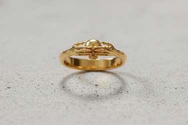 Gold vermeil death claddagh ring featuring skeletal hands holding a skull on neutral background