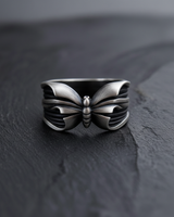 Front view of sterling silver butterfly ring with oxidized finish and detailed wing texture on dark slate background