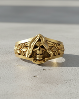 Gold vermeil grim reaper ring with hooded skull and floral band details on concrete background