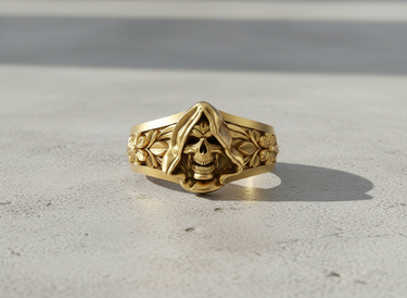 Gold vermeil grim reaper ring with hooded skull and floral band details on concrete background