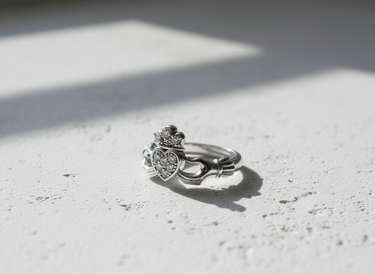 Elegant 925 sterling silver Claddagh ring featuring a crowned heart with sparkling stones on a white textured background