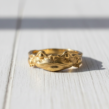 Front view of 14K gold vermeil silver frog ring featuring textured skin and bulging eyes on white wood