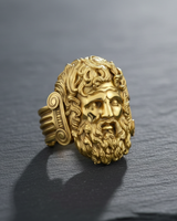 Gold vermeil Zeus ring featuring detailed bearded face of Greek god Jupiter on dark stone background