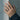 Baby feet ring worn on model hand against a concrete wall