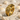Close-up of luxurious 14K gold vermeil falcon ring showcasing detailed metalwork resting on a sandy beach surface