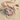 Close-up of rose gold plated Aquarius Zodiac Pendant resting on textured sand showcasing intricate metal craftsmanship