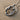 Handcrafted sterling silver bird letter O pendant resting on a beautiful seashell upon warm golden beach sand