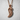 Resting Swan Pendant, rose gold, hanging on chain against wall