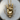 Close-up of the rock on skull pendant resting on a natural wood slice highlighting the masterfully crafted 3D details
