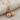 Twin Cherry Pendant, rose gold, angled view on fabric
