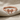 Petite Bow Ring, rose gold, front view on textured fabric